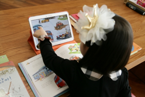 웅진북클럽 회원이 태블릿PC를 이용해 책을 읽고 있다. 사진=웅진씽크빅