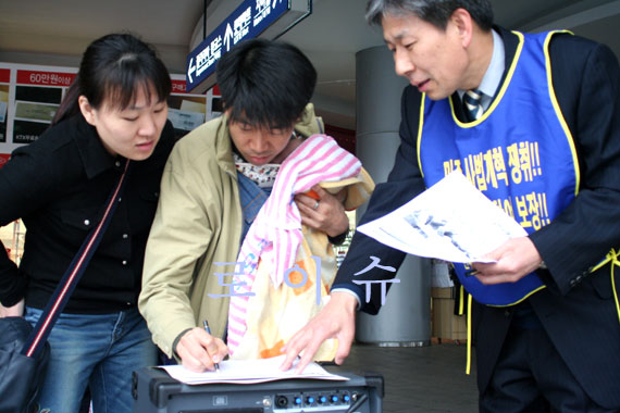 ▲정용상공동집행위원장(우측)이시민들에게올바른로스쿨법제정취지를설명하며서명을이끌어내고있다.아기를안고고향으로내려가기위해서울역에온이들부부는기자와인터뷰도했다.