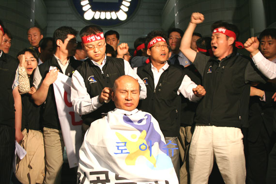 ▲곽승주위원장이삭발하는동안경비대원들에둘러싸인법원노조간부들이"사법개혁"구호를외치고있다.