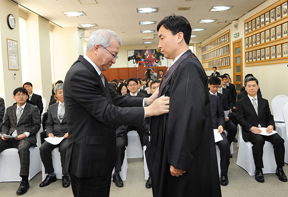 ▲양승태대법원장이연임법관표극창서울서부지법판사에게법복을입혀주고있다(사진=대법원)