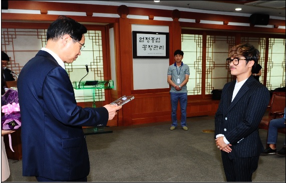 ▲중앙선관위김용희사무총장이8일과천청사에서울랄라세션멤버인김명훈에게선(選)남선(選)녀서포터즈위촉장을전달하고있다.