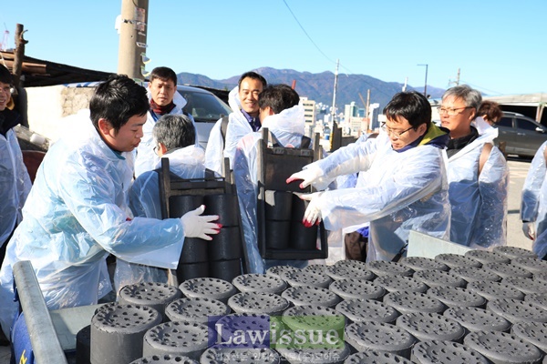 부산선관위 선한모임 회원들이 연탄을 지게에 올리고 있다.