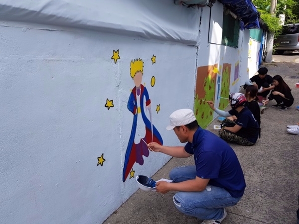낙후된 담벼락에 그림을 그려넣고 있다.