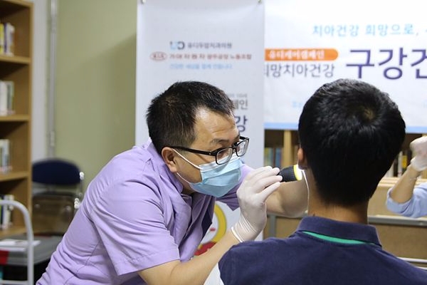 유디치과(광주두암점) 대표원장이 행사에 참석한 장애인의 치아를 검진하는 모습