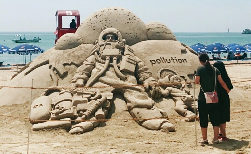 ‘2017 한국필립모리스 바다사랑 캠페인’의 일환으로 부산 송정 해수욕장에 마련된 환경 주제 모래 조형 작품을 감상하는 피서객의 모습.(제공=한국필립모리스)
