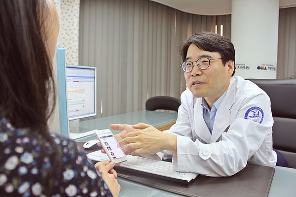 강남차병원여성의학연구소 류상우 교수가 환자에게 카카오 알림톡 서비스 사용법을 알려주고 있다(사진:강남차병원 제공)