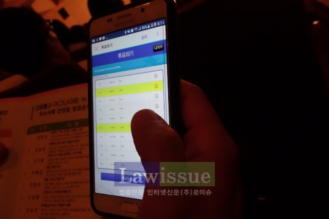 청중단이 스마트폰으로 우수팀을 선발하고 있다.