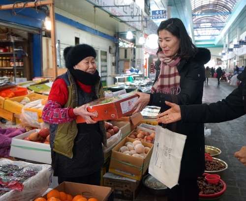 김외숙 법제처장(오른쪽)이 공주산성시장을 방문, 시장상인들로부터 과일을 구입하고 있다(사진=법제처 제공)