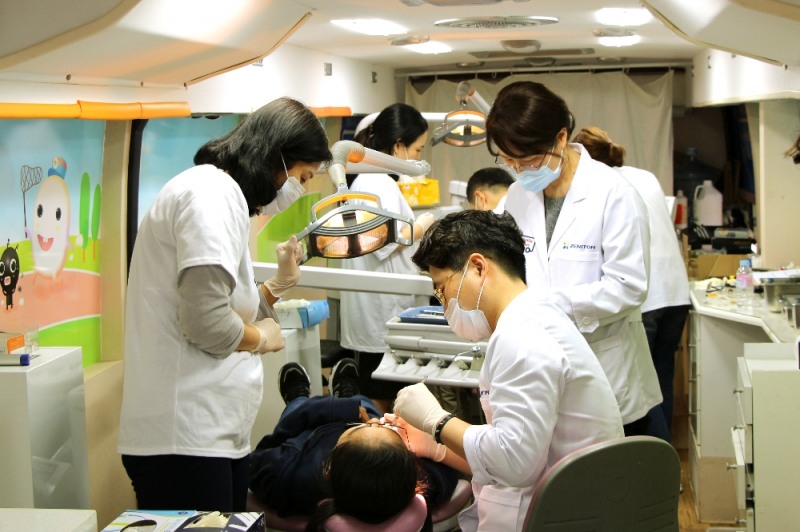 지난 1일 서울시 영등포구 대림3동 서울온드림교육센터를 방문한 제니튼 지대경 대표(오른쪽에서 두 번째)를 비롯한 ‘해피스마일 치과버스’ 의료봉사단이 중도입국 청소년들을 진료하고 있다.(사진=제니튼)