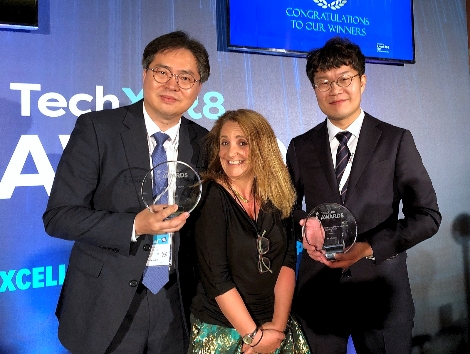 12일(현지시간) 영국 런던에서 열린 ‘TechXLR8 2018’ 시상식 후 SK텔레콤 조성호 Access Network 랩장(사진 왼쪽)과 이동기 박사(오른쪽)가 사회자와 기념촬영을 하고 있는 모습. (사진=SK텔레콤)