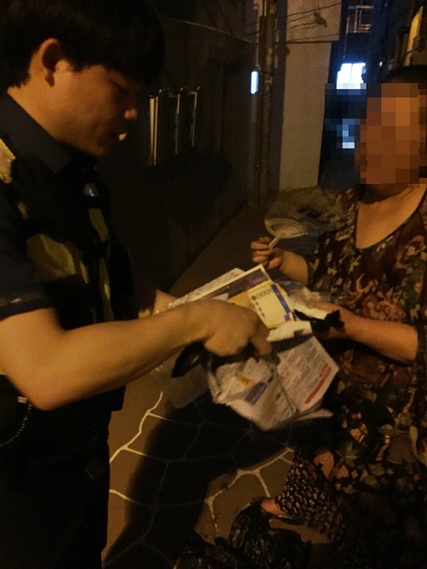 정민기 순경이 쓰레기더미에서 돈몽치를 찾아 건네주고 있다.(사진제공=부산지방경찰청)