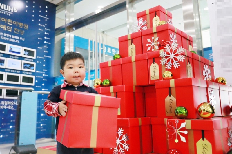위시트리 이벤트에 참여한 환아가 크리스마스 선물 소원을 빌며 상자를 쌓고 있다.(사진=한화갤러리아)