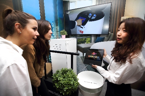 25일(현지시간) KT 전시관 내 5G AI 호텔 로봇 존에서 관람객이 AI 호텔 로봇 서비스를 체험하고 있다. 사진=KT
