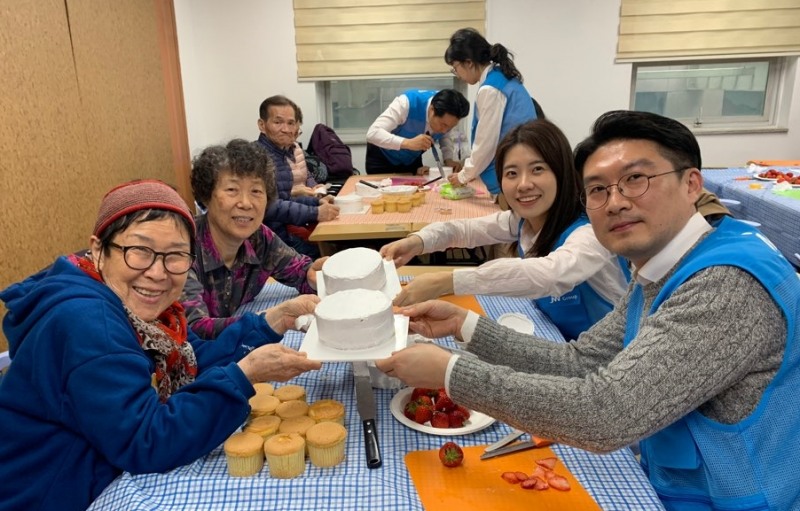 JW한마음봉사단원들이 어르신들과 케이크를 만들고 기념촬영을 하고 있다. (사진=JW그룹)