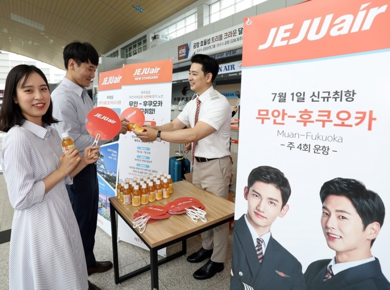 제주항공 승무윈이 7월1일 오후 무안국제공항에서 무안~후쿠오카 탑승객들에게 제주산 감귤 과즙음료와 부채를 건네주고 있다. (사진=제주항공)