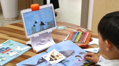 웅진북클럽 회원이 직접 색칠한 물고기를 인터랙티브북 화면에 구현하고 있다. 사진=웅진씽크빅