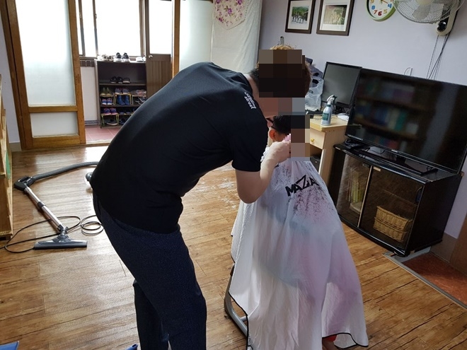 미용기술을 가진 사회봉사대상자가 아동의 머리를 손질하고 있다.(사진제공=진주준법지원센터)
