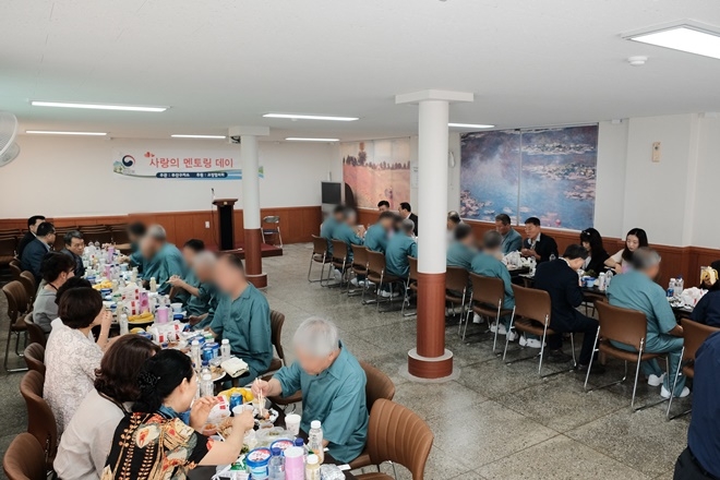 교정위원과 고령수형자가 고충상담을 하며 음식을 나눠 먹고 있다.(사진제공=부산구치소)