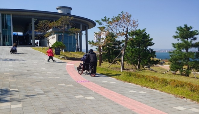 사회봉사대상자가 외부체험 행사에 나온 장애인의 휠체어를 밀어주고 있다.(사진제공=포항준법지원센터)