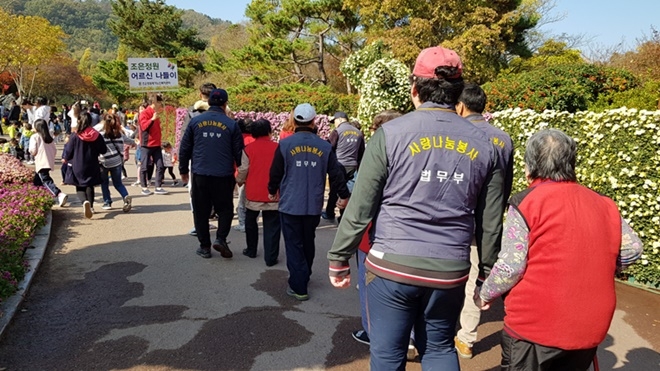 어르신들의 손을 맞잡고 국화축제 나들이 행사를 돕고 있다.(사진제공=대구서부준법지원센터)