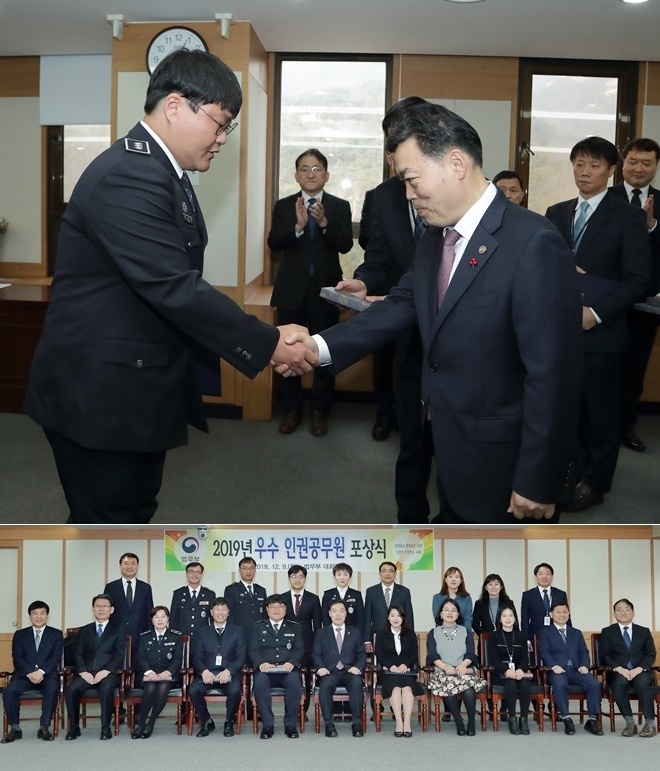 김오수 법무부 장관 직무대행이 9일 정부과천청사에서 개최된 ‘2019년 우수 인권 공무원 포상식’에서 송상헌 교도관(왼쪽)에게 표창하고 수상자들과 기념촬영을 하고 있다.(사진제공=법무부)