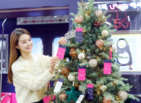 모델이 U+5G 갤러리 소원트리에 소원카드를 걸고 있다. 사진=LG유플러스