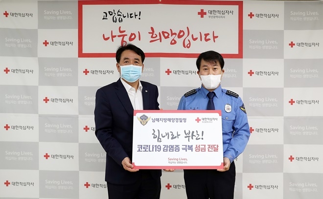 남해해경청 박상욱 경비과장이 20일 코로나19 극복을 위한 성금을 대한적십자사 부산지사 조호규 사무처장에게 전달하고 있다.(사진제공=남해지방해양경찰청)