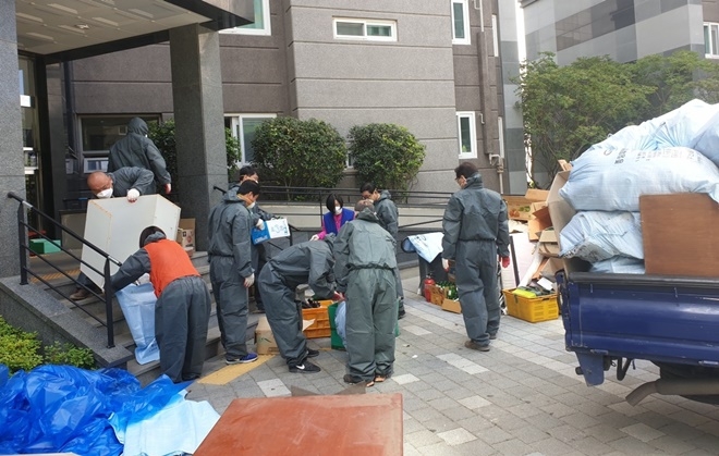 사례관리대상자의 방치된 쓰레기와 물건을 치우고 있다.(사진제공=부산기장군)