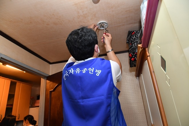 자총 금정구지회 통일마중물 봉사단이 북한이틸주민 가구에 LED조명 교체작업을 하고 있다.(사진제공=부산금정구)
