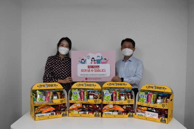 (오른쪽)롯데건설 외주구매본부장 석균성 전무가 파트너사에 제공한 롯데제과 간식 자판기에서 촬영을 하고 있다.(사진=롯데건설)