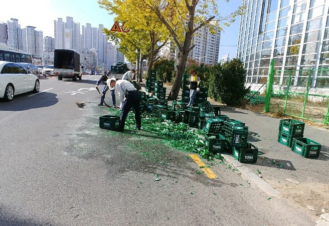 11월 12일 오전 동래구 연안교 입구 도로에 빈 맥주병 60박스가 낙화돼 경찰이 함께 치우고 있다.(사진제공=부산경찰청)