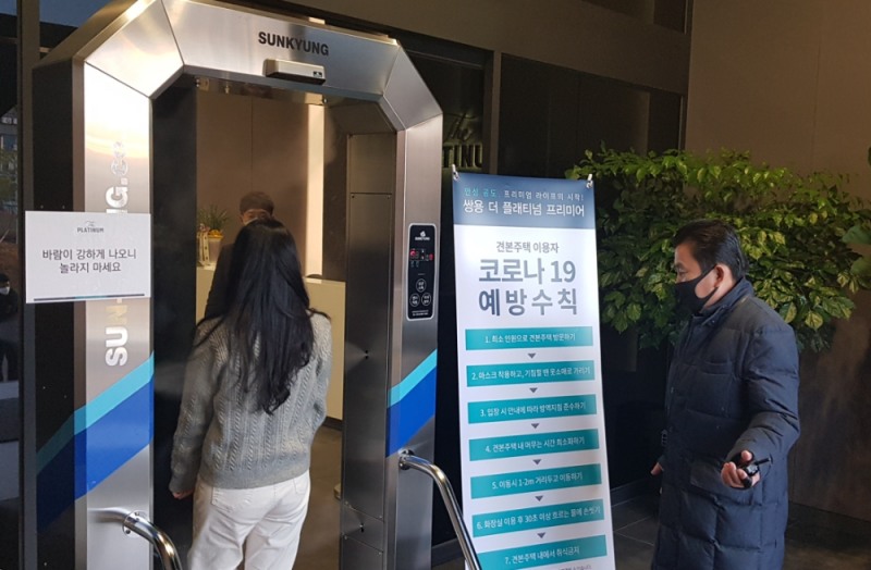 지난 18일 오픈한 '쌍용 더 플래티넘 프리미어' 견본주택을 찾은 방문객들이 입장 전 터널형 전신 소독기를 통과하는 모습.(사진=쌍용건설)