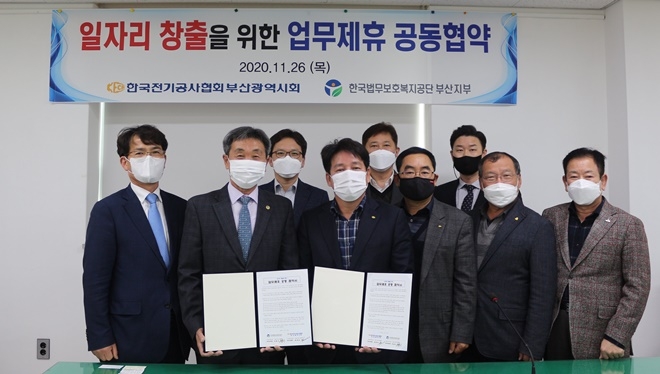 이흥수 공단 부산지부장(왼쪽 두번째)과 문병호 시회장이 업무협약서를 내보이며 기념촬영을 하고 있다.(사진제공=한국법무보호복지공단부산지부)