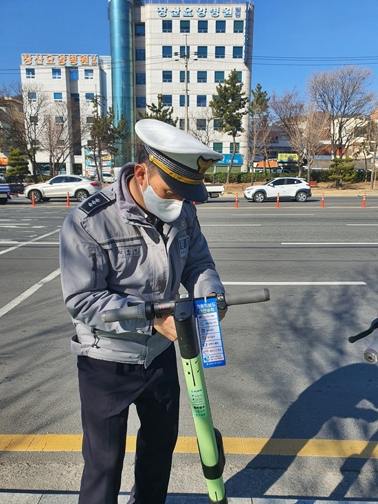 경찰관이 킥보드에 교통안전수칙 홍보문구를 부착하고 있다.(사진제공=창원서부경찰서)