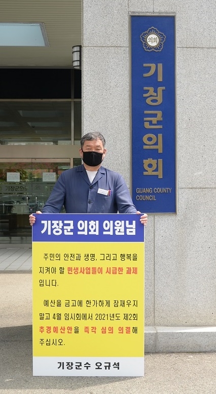 오규석 기장군수가 16일 낮 12시 기장군의회 정문에서 2021년도 제2회 추경예산안의 조속한 심의를 촉구하며 1인 시위를 벌이고 있다.(사진제공=부산 기장군)
