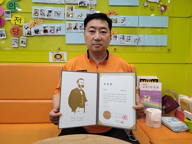 이호근 소방위가 헌혈 100회 달성 공로로 수상한 명예장을 내보이며 기념촬영.(사진제공=울산시)