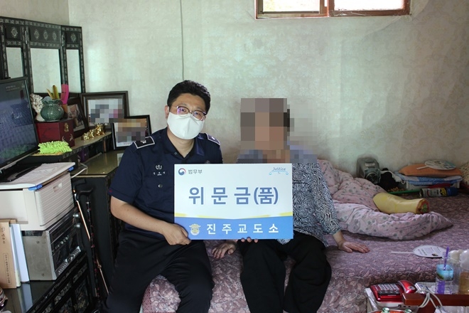 정주영 교위가 보훈가정에 위문금을 전달하고 위로를 하고 있다.(사진제공=진주교도소)