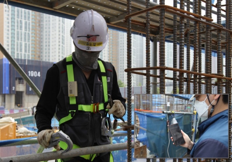 포스코건설 공사 현장에서 작업자가 스마트 안전벨트의 알람을 듣고 안전고리를 체결하고 있으며, 안전관리자는 모바일로 작업자의 안전고리 미체결 상태를 확인하고 있다.(사진=포스코건설)