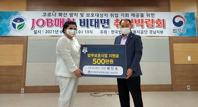 6월 21일 배인숙 운영위원회 위원장이 김성균 지부장에게 지원금을 전달하고 기념촬영.(사진제공=한국법무보호복지공단경남지부)