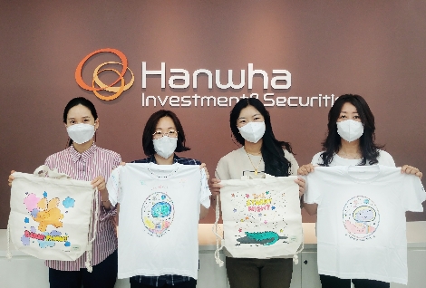 한화투자증권 임직원들이 해외 아동을 위해 제작한 에코백과 티셔츠를 들고 기념사진을 촬영하고 있다. 사진=한화투자증권