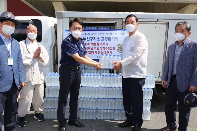 양진웅 부산구치소 교정협의회장이 8월 4일 김영식 부산구치소장에게 수용자를 위한 생수를 전달하고 있다.(사진제공=부산구치소)