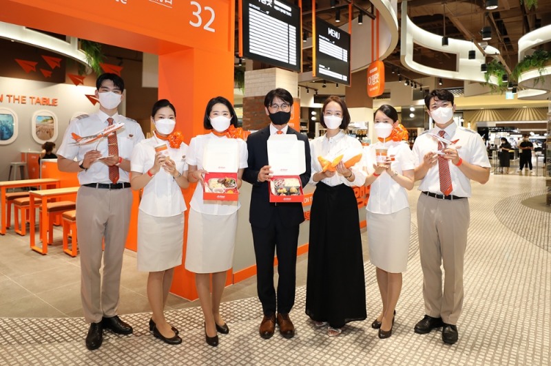 여행맛’ 2호점 오픈행사에서 AK플라자 김재천 대표이사(사진 왼쪽 네번째)와 제주항공 장주녀 객실본부장(사진 오른쪽 세번째)이 승무원과 함께 기념촬영을 하고 있다.(사진=제주항공)