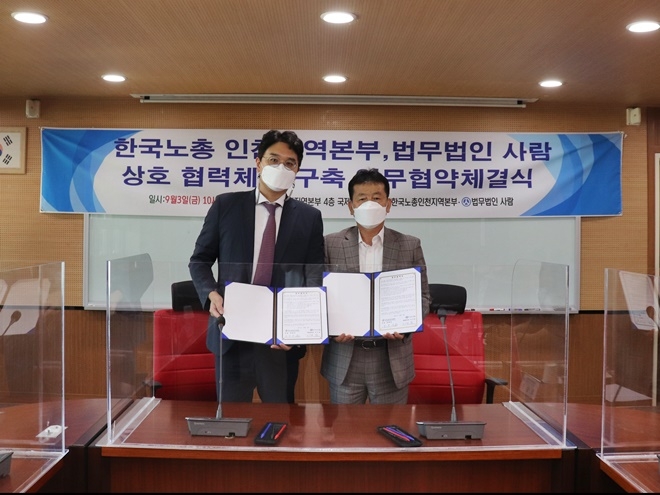 (왼쪽부터) 법무법인 사람 이기윤 대표, 한국노총 인천지역본부 김영국 의장이 업무협약서를 내보이며 기념촬영.(사진제공=법무법인 사람)
