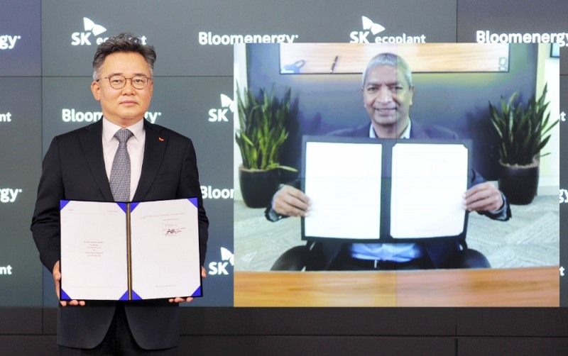 박경일 SK에코플랜트 대표이사(왼쪽)와 케이알 스리다르(KR Sridhar) 블룸에너지 창업자 겸 최고경영자(CEO)가 온라인 화상시스템을 통해 계약서를 들고 기념촬영을 하고 있는 모습.(사진=SK에코플랜트)