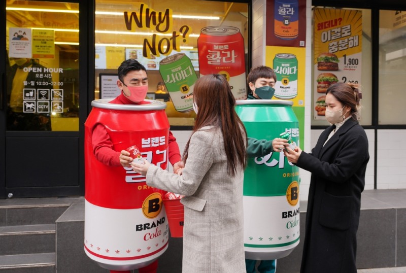 <사진설명 : 14일 서울 중구 무교동 노브랜드 버거 서울시청점 앞에서 신세계푸드 송현석 대표이사와 이대희 수원호매실점 브랜드 파트너(가맹점주)가 이날 론칭한 ‘브랜드 콜라’와 ‘브랜드 사이다’를 알리기 위해 특별 제작한 콜라맨, 사이다맨 의상을 착용하고 직접 제품을 나눠주며 홍보에 나섰다. 노브랜드 버거의 ‘브랜드 콜라’, ‘브랜드 사이다’는 노브랜드 버거 만의 독자적 브랜드 경험을 주기 위해 개발한 것으로 빨강색과 초록색에 흰색을 배색으로 조합하고, 브랜드를 뜻하는 노란색의 ‘B’로고를 비롯해 패키지 곳곳에 팝아트적 요소를 넣어 예술품과 같은 느낌을 주는 것이 특징이다. 전국 노브랜드 버거 매장에서 배달 및 포장 구매시 제공된다.>