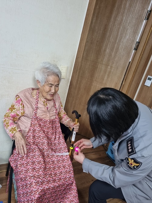 경찰이 야간·새벽시간대 안전보행을 위한 ‘불빛 펜던트’를 지팡이에 부착하고 있다.(사진제공=창원서부경찰서)