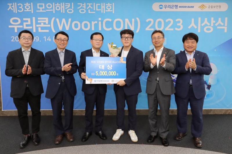 우리은행은 지난 14일 서울 중구 소재 우리은행 본점에서 제3회 모의해킹 경진대회 '우리콘(WooriCON) 시상식을 개최했다. 조병규 우리은행장(왼쪽 세번째), 김철웅 금융보안원장(오른쪽 두번째), 김백수 우리은행 정보보호그룹 부행장(오른쪽 첫번째), 박춘식 아주대학교 교수(왼쪽 두번째), 고려대 김휘강 교수(왼쪽 첫번째)가 대상 수상자와 기념촬영을 하고 있다. 사진=우리은행