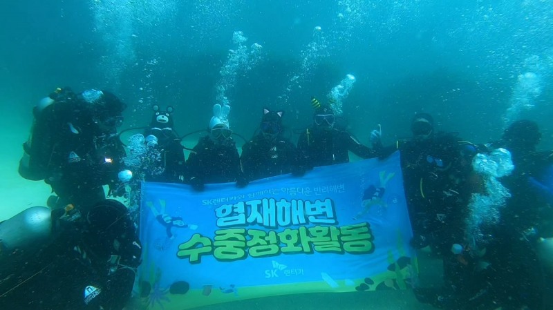 제주 협재해변 수중 정화활동에 나선 SK렌터카 사내 스킨스쿠버동호회 ‘윤슬.Sea’, 해양환경보호단체 ‘오션케어’, UDT 자원봉사단 ‘바다살리기 운동본부’, 이호어촌계 해녀 등이 기념사진을 촬영하고 있다.(사진=SK렌터카)