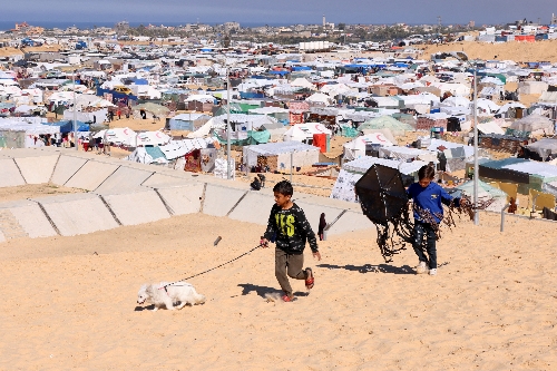 [사진=연합뉴스] 팔레스타인 가자지구 남부 라파에서 팔레스타인인들이 텐트로 만들어진 피란민 캠프로 피신하고 있는 가운데 아이들이 강아지와 걷고 있다.