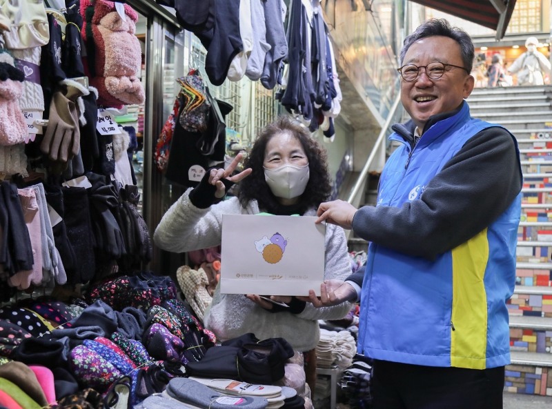 지난 22일 서울시 중구 소재 남대문시장 일대에서 ‘설맞이 상생캠페인’을 진행하고 신한은행 정상혁 은행장이 시장 소상공인에게 선물을 전달하고 기념촬영하는 모습. 사진=신한은행